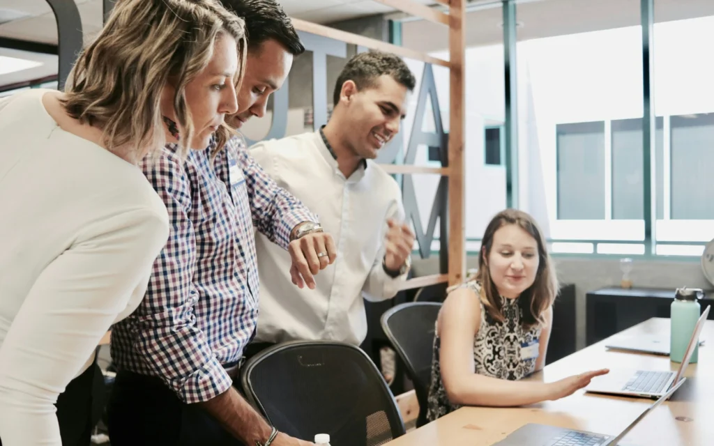 Team in moderner Bürosituation bei gemeinsamer Arbeit am Laptop – Beispiel für systemisches Business Coaching in Hamburg